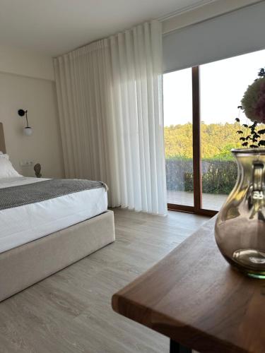 塞洛里库迪巴什图Villa Deluxe - Quinta do Outeirinho的一间卧室配有一张床和一张桌子,上面有花瓶