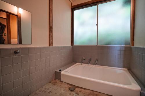 热海new! 熱海桃山邸　Atami terrace villa 〜Sauna & Onsen 〜的带浴缸的浴室和窗户