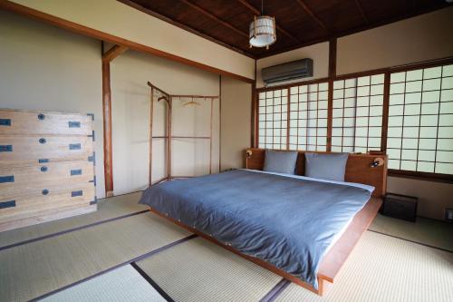 热海new! 熱海桃山邸　Atami terrace villa 〜Sauna & Onsen 〜的一间设有蓝色床的卧室,位于带窗户的房间内