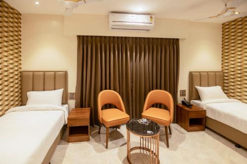 孟买The Majestic Boutique Hotel的酒店客房带两张床和一张桌子以及椅子。