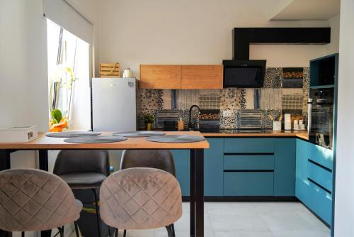 布泽特Stunning new apartment in centre of Buzet的厨房配有蓝色橱柜和带凳子的桌子