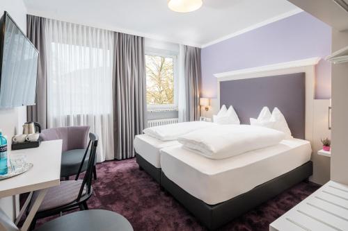 比斯平根Flair Hotel Rieckmann的酒店客房设有一张大床和一张书桌。