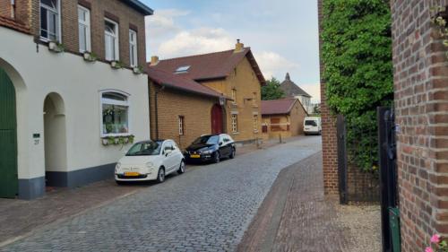 埃尔斯洛Boerderijwoning Elsloo的两辆汽车停在建筑物旁边的街道上