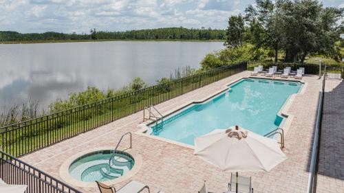 迈尔斯堡Crowne Plaza Ft Myers Gulf Coast, an IHG Hotel的湖畔带遮阳伞的游泳池