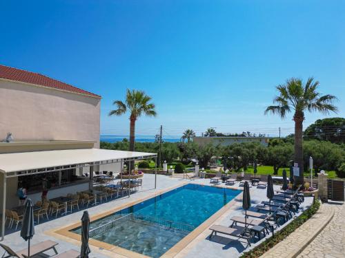 阿莫迪Remezzo Studios & Apartments的一个带椅子和棕榈树的度假村游泳池