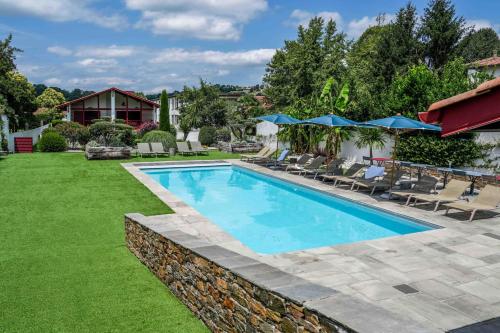阿斯帕朗爱吉亚酒店的庭院内的游泳池,配有椅子和遮阳伞