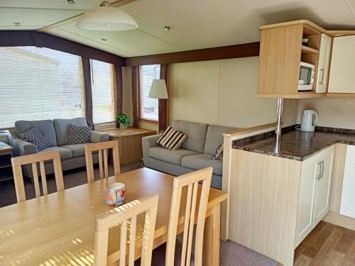 普利斯坦丁2 Bedroom Static Caravan C3 on quiet park near Talacre and Prestatyn的厨房以及带桌子和沙发的客厅。