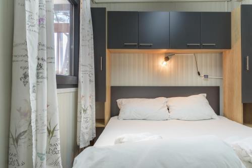 比奥格勒·纳·莫鲁比奥格勒移动露营之家酒店的一间卧室配有一张白色的床和黑色橱柜。