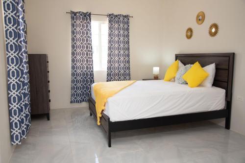 迪斯卡弗里贝OceanView Villa的一间卧室配有黄色和蓝色窗帘的床