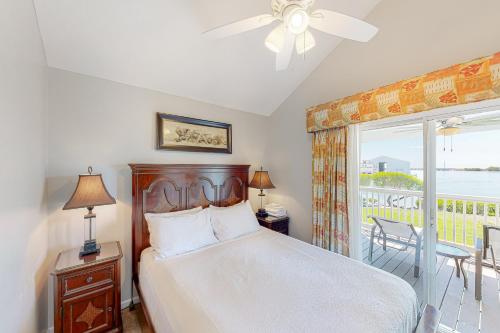 鸭礁岛C est la Vie的一间卧室配有一张带吊扇的床和一个阳台