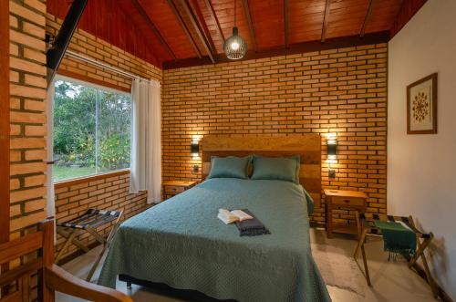 维奥康德马奥Chalé Flores e Amores的一间卧室设有一张床和砖墙