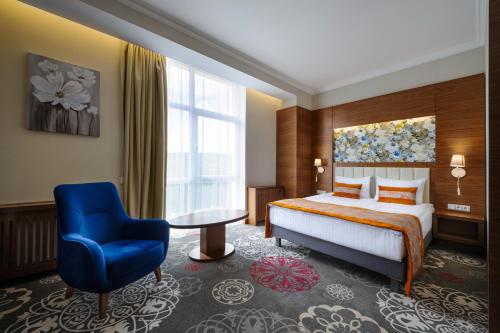 萨塔尼夫ARDEN PALACE Medical Resort & SPA的酒店客房,配有一张床和一张蓝色椅子