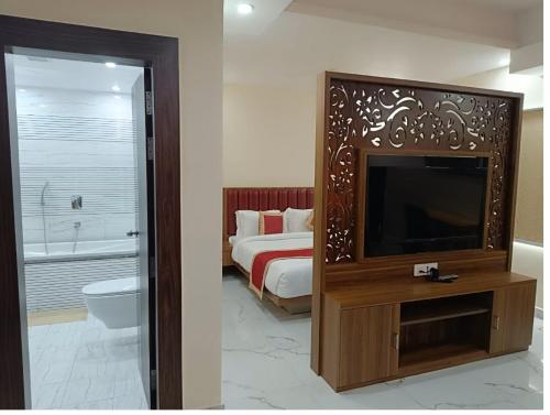 穆扎夫法尔普尔Hotel Paramveer的一间卧室配有一张床和一台电视,还设有一间浴室