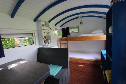 OudesluisTiny house Roodborstje的一间设有双层床的房间和一张火车上的桌子