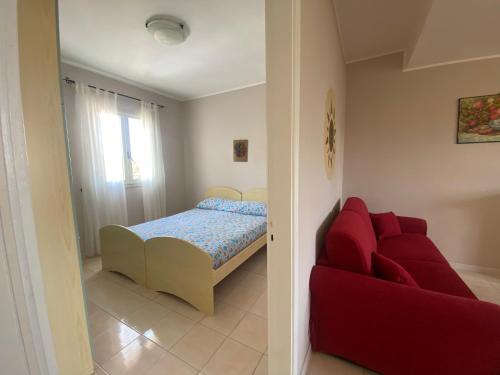 托雷莫泽Villetta Sabbia d'Oro的一间卧室配有一张床和一张红色的沙发