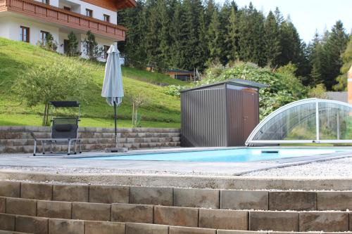 安纳贝格-伦格茨萨尔茨堡多罗米特诺夫酒店的一个带遮阳伞、椅子和桌子的游泳池