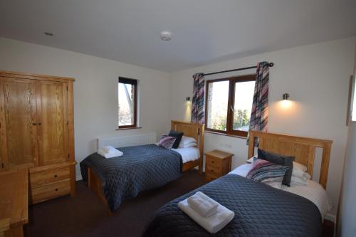 彭里斯Aikbeck Lodge的一间卧室设有两张床和窗户。