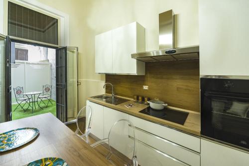 卡塔尼亚Appartamento Martoglio - Casa Vacanze -的厨房配有白色橱柜、水槽和桌子