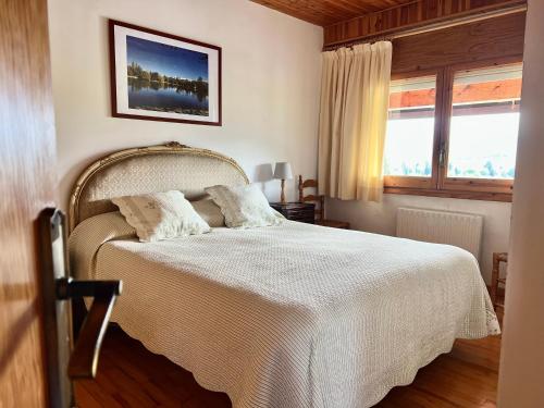 普奇塞达Piso Puigcerda vistas y piscina的一间卧室配有一张带白色床单的床和一扇窗户。