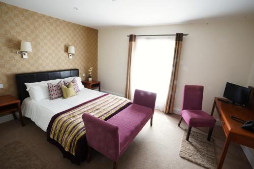 马拉费尔特The Castledawson Inn的一间卧室配有一张带紫色椅子的床和一张书桌