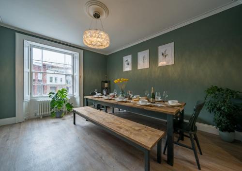 布里斯托Clifton Town House with Cinema Room Perfect for Groups, Families, Friends Hens & Stags!的一间带桌子和长凳的用餐室