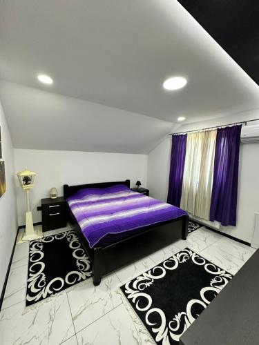 瓦列沃Vila Veselić的一间卧室配有一张紫色的床和两张地毯。