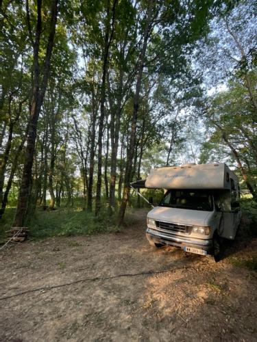 MiélanLocation atypique en camping car americain au bord du lac de Miélan, proche de Marciac的停在树林里的土路上的卡车