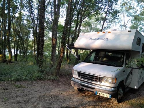 MiélanLocation atypique en camping car americain au bord du lac de Miélan, proche de Marciac的一辆白色的卡车停在树林里