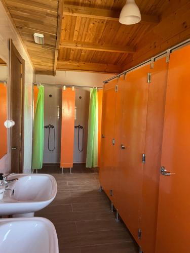 圣马丁德拉韦加Granja escuela con Bungalows的浴室设有两个水槽和橙色及绿色的摊位。