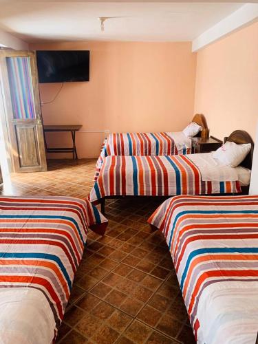 查查波亚斯Fidelísima Hotel的酒店客房,配有两张带条纹床单的床