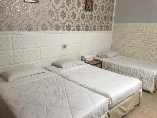 JertihLily Budget Hotel的配有白色床单的客房内的两张床