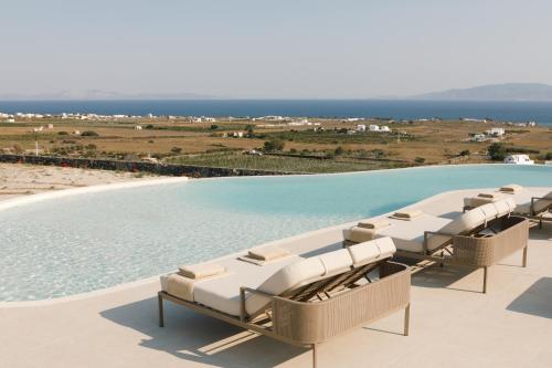 伊亚Elysian Retreat的一个带椅子的游泳池,背景是大海
