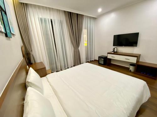 下龙湾MOONLIGHT HOTEL的卧室配有白色的床和平面电视。