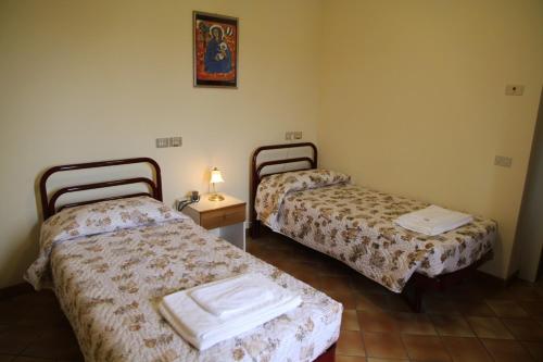 洛雷托Hotel Madonna di Loreto的客房设有两张床和一张带台灯的桌子。