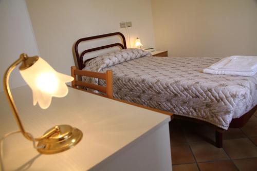 洛雷托Hotel Madonna di Loreto的一间卧室配有一张床和一张带台灯的桌子