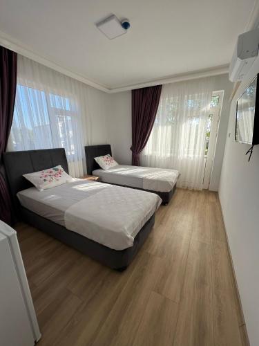 安塔利亚Asimado Hotel的客房内设有两张床,配有木地板和窗户。