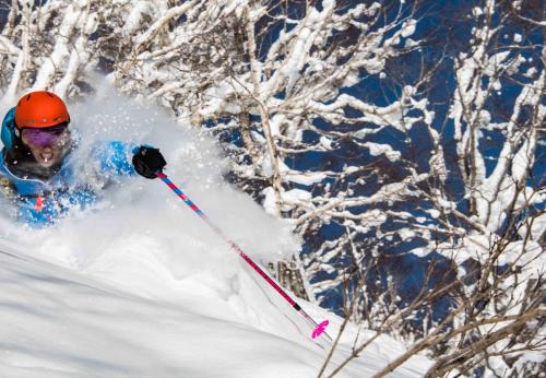 妙高妙高森野山林小屋的一个人在雪覆盖的斜坡上滑雪