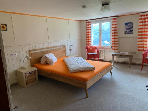 维尔德豪斯Zimmer & z'Morgä Schönenboden的一间卧室配有一张带橙色床单和椅子的床