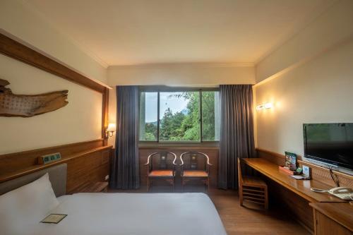 鹿谷乡孟宗山庄大饭店的酒店客房,配有床和电视