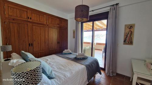 阿尔姆尼卡Los Cipreses - Casa Ola的一间卧室设有一张床和一个大窗户