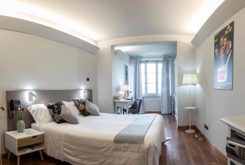 科尔托纳Locanda agli Amici的白色卧室配有一张大床和一张书桌