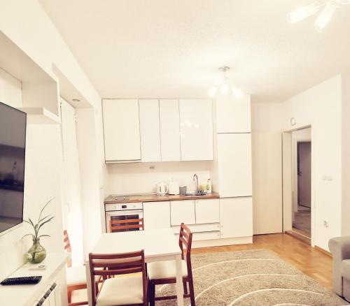 普里莱普Central apartment in Prilep的厨房配有白色橱柜和桌椅