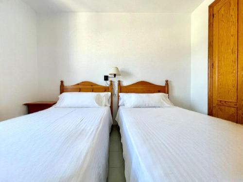 滨海罗克塔斯Beachfront apartment in Roquetas de Mar with communal pool的卧室内两张并排的床