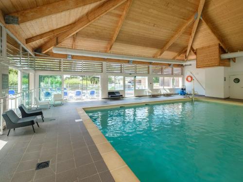 索米尔Beautiful maisonnette with included linen package in Saumur的一个带蓝色椅子和天花板的室内游泳池