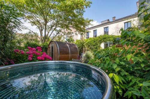 拉罗谢尔Escale Rochelaise, gîte urbain avec SPA bain nordique et sauna tonneau的花园内的一个玻璃浴缸,有一个桶