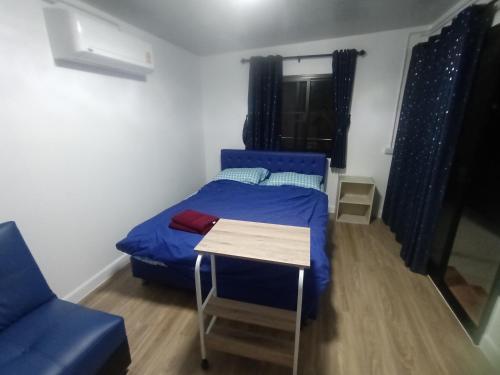 曼谷帕豪斯公寓的一间设有蓝色床和一张桌子的小卧室