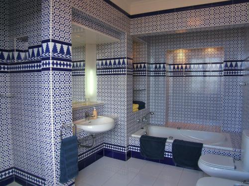 拉奥罗塔瓦阿尔罕布拉酒店的浴室拥有蓝色和白色的瓷砖墙壁,配有浴缸和水槽