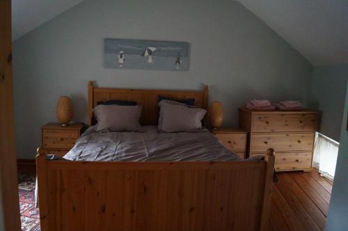 Sart lez WalhainLa Petite Maison的一间卧室配有木床和2个梳妆台。