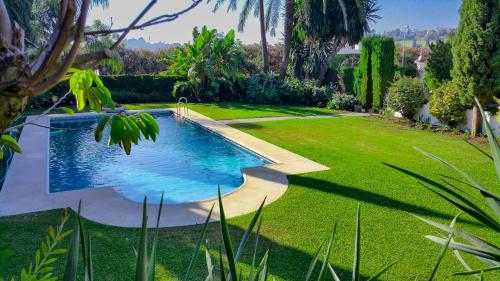 EsteponaCortijo De Cortes的花园内的一个游泳池,花园内种有草地和树木