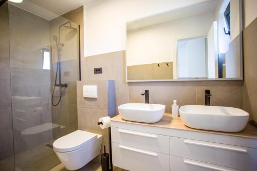 帕科坦Villa Favi的浴室配有2个盥洗盆、卫生间和淋浴。